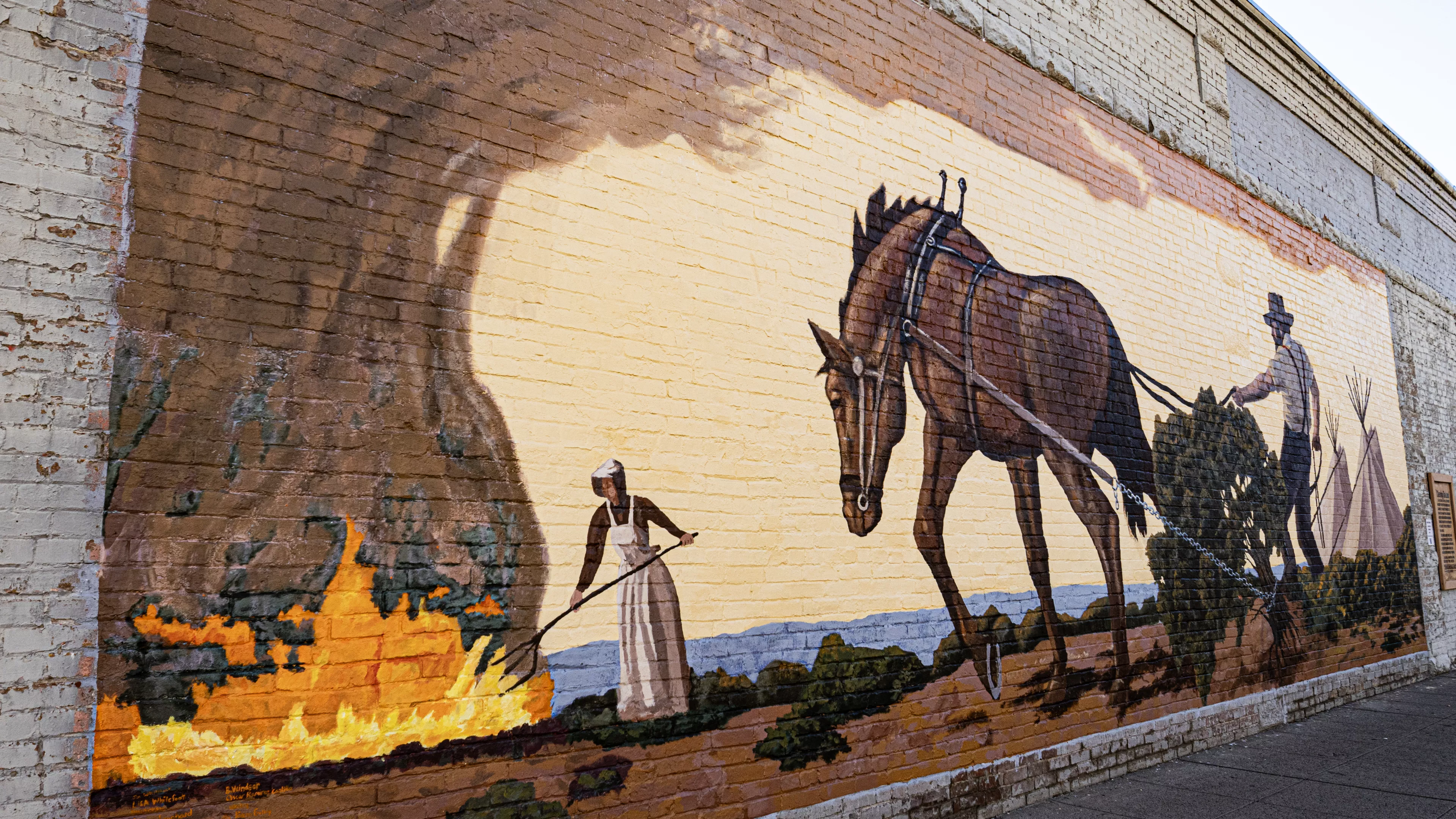 Mural painting  of a woman tending a fire and a man plowing a field with a horse.